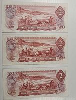 Reverse side of three 1974 Canadian $2 notes showing Inuit hunting scene and denomination