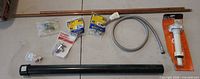 Grouped view of copper pipes, PVC pipe, braided hose, toilet fill valve package, angle stop valve, and several small sealed fittings