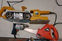 Top view of four corded Black & Decker tools laid out: belt sander, dual-action sander, drill/driver, jigsaw
