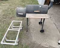 Smoker on stand with wheels adjacent to PVC rack