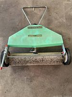 Top view of Danville Express green lawn seeder with hopper, roller, wheels, handle
