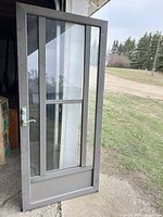 Front view of gray aluminum storm door showing full glass panel, mullions and bottom screen section
