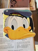 Shaped children’s Donald Duck book atop loose sheet music pages