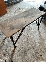 Full view of rectangular plywood-top work bench with metal legs