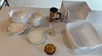 Group view of all ceramic dishes, silicone lids, mug, candlestick, ashtray, and plastic bins