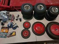 Overall lot showing stacked tires, red wheels, casters, bearing caps, Kenda sealant