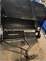 Full view of RedRock tow-behind lawn sweeper showing frame, hitch, wheels, brush bar and collection bag