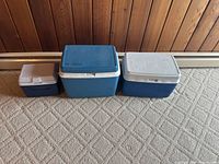 Front view of three Rubbermaid blue and white coolers in ascending size