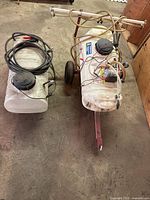 Both sprayers showing tanks, hoses, tow frame