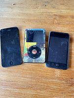 Front view of iPhone 5, iPod Classic with skin, iPod Touch on wood surface