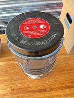 Top view showing black lid with red instruction label and overall canister shape