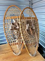Full view of both wooden snowshoes standing side by side