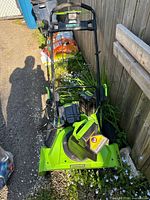 Full view of Greenworks snow blower with battery and charger on unit