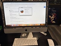 Front view of iMac powered on with keyboard, mouse, and USB drive visible