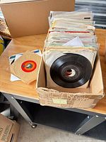 Box holding roughly 40 paper-sleeved 7" vinyl singles