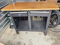 Front view of workbench showing wood top, drawers, open lower shelf structure