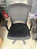 Front view of Staples mesh manager chair showing mesh back, fabric seat, adjustable armrests, swivel base