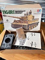 Box lid showing Tamiya Tiger I kit with open carton displaying parts, instructions, photo-etch sheet