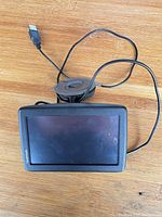 Front view of TomTom GPS with attached suction mount and USB cable