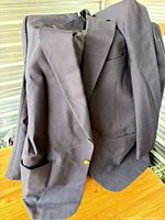 Full view of navy sport coat on hanger showing front, pockets and button
