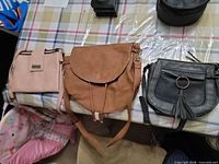 Three handbags laid out: blush Jordache, tan JustFab, black unbranded