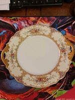 Front view showing floral pattern, gold handles and decorative rim