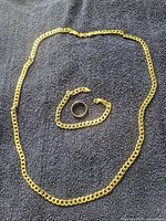 Necklace, bracelet and ring laid flat on dark fabric