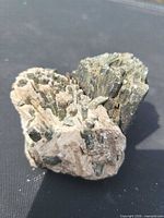 Top view of green prismatic tourmaline crystals embedded in tan matrix