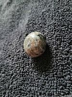 Overall view of the polished spherical Yooperlite stone on fabric