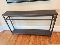 Front view of black metal console table showing top shelf and lower shelf