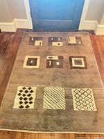 Full view of rug at doorway showing geometric square motifs and overall color