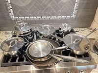 Full set of pots, pans, and lids displayed on stovetop