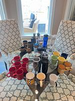 Full assortment on glass table: mugs, tumblers, bottles, glasses, pitcher