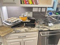 All items stacked on countertop showing variety of pans, bowl, measuring cup, jars