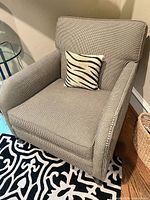 Full view of the beige houndstooth armchair with zebra pillow