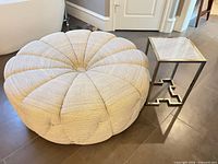 round beige ottoman alongside chrome side table