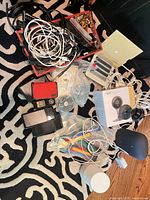 Overview of lot showing Nest camera box, cables, power banks, charging dock and accessories on rug