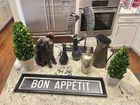 All items arranged on countertop: pig statue, two topiaries, two bird figures, horn display, pitcher, gold bottle, Bon Appétit sign