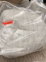 White tufted king comforter sealed in clear zip storage bag
