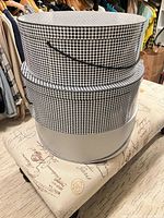 Stack of two round houndstooth-pattern containers likely holding the sun hat