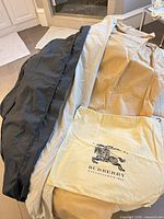 Garment bags and Burberry dust bag displayed on surface