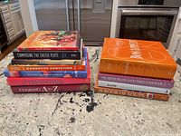 Two stacks of cookbooks on countertop showing titles and spine condition