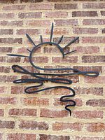 flat metal sun and wave wall art against brick