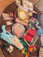 Overview of lot on table showing water gun, plush toys, plates, napkins, gift bags, ribbons, Rubik’s Cube