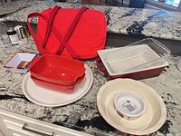 All items displayed together on countertop including tote, baking dishes, serving dish, cat bowl