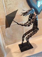 Full view of sculpture on base showing pose and umbrella