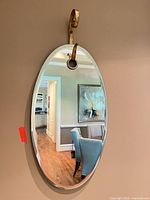 Frameless oval mirror hanging on wall showing overall appearance and hanger