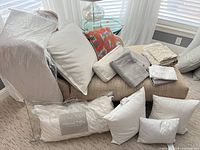 Group view of pillows, inserts and folded coverlets on chaise