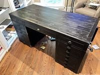 Full view of black distressed wood desk showing twin pedestals and plank top