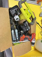 Box containing Ryobi blower handle, chargers and batteries